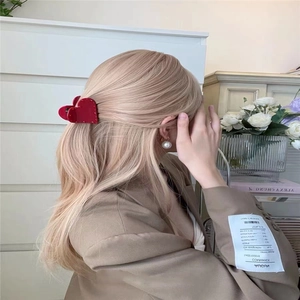 Eleganter roter Haarklammer in Herzform für Damen auf blonden Haaren gezeigt