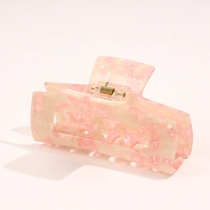 Close-up of pink and cream marble acetate hair claw clip with golden metal spring