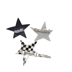 Close-up of three star hair clips in glitter black, silver, and checkerboard pattern