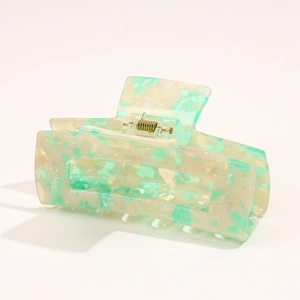 Close-up of mint green marble acetate hair claw clip with golden metal spring