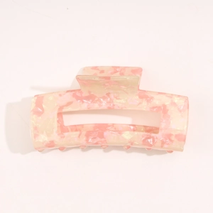 Detail view of pink and yellow marble acetate hair claw clip with a hollow rectangular shape