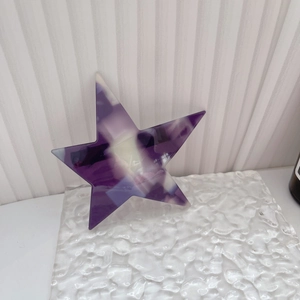 Detailed macro view of purple and white checkered acetate star hair clip on icy background