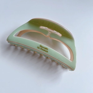 Detail of hollow acetate hair claw in light green and pink with Barrette la France logo