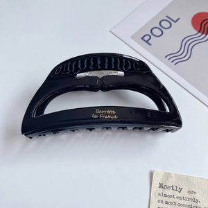 Detail of a black acetate shark hair claw featuring golden Barrette La France text