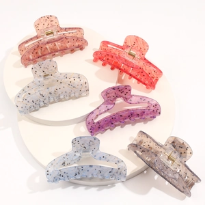Close-up of six colorful acetate shark hair claws with gold springs and speckled patterns