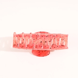 Detail of large rectangular coral pink acetate hair claw with black sequin embellishments