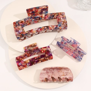 Detailed view of four assorted acetate hair claws with shell patterns on a white platform