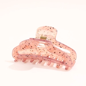 Macro shot of large acetate hair claw clip with pink marble texture and gold glitter flakes
