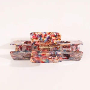 Close-up of a floral acetate hair claw clip showing the colorful marble pattern and gold spring