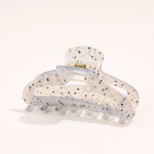 Close-up of a large acetate hair claw clip with abstract blue and yellow patterns