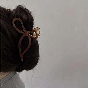 Détail d'une grande pince à cheveux marron en acétate avec un nœud sur la tête