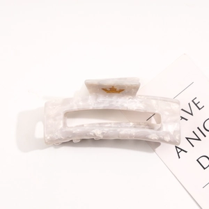 Close-up of marble pattern acetate hair claw clip with a gold crown motif detail