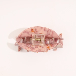 Detail view of pink marble acetate hair claw clip with golden metal spring mechanism