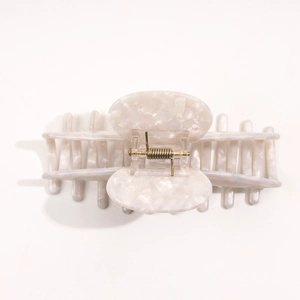 Macro shot of large cream acetate hair claw clip showing smooth texture and metal spring
