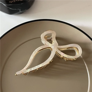 Détail de la grande pince à cheveux en acétate crème marbré avec base en métal doré