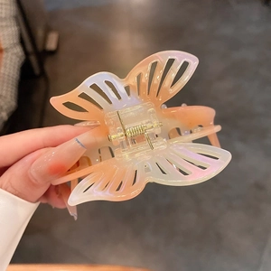 Detailed close-up of a butterfly hair claw clip with iridescent pink and orange finish