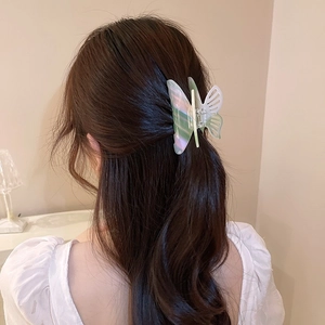 Close-up of a gradient butterfly hair claw clip with pearlescent finish on long wavy hair