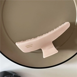 Détail macro d'une grande pince à cheveux rose mat avec lettrage français sur plateau