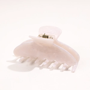 Detail of light pink acetate hair claw clip with marble texture and gold metal spring