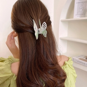 Close-up of a pearlescent white and green gradient butterfly hair claw clip on long hair