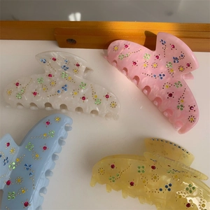 Close-up of acetic acid hair claws with colorful rhinestones and pearlescent finish
