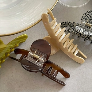 Detail view of four acetate claw clips in tortoiseshell, cream, green and leopard print