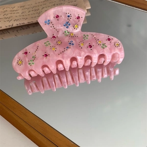 Macro shot of pink marble acetate hair claw with multi-color rhinestones on mirror