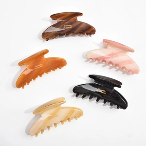 Five assorted colors of acetate hair claws arranged in a decorative fan layout