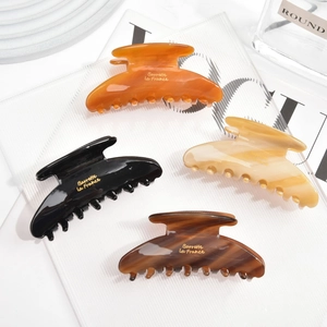 Macro detail of large acetate hair claws in amber, black, and marble textures