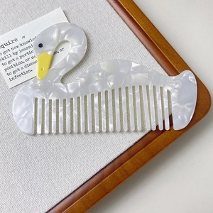 Detailed view of swan shaped acetate hair comb with white pearl texture and wide teeth
