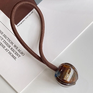 Détail macro d'une perle en ambre avec texte France Handmade sur élastique marron