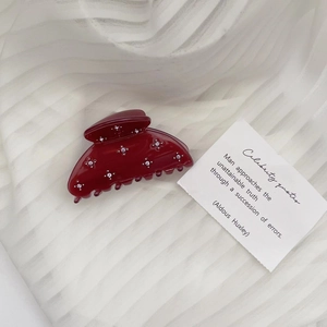 Detailed view of dark red acetate hair claw clip with silver flower and rhinestone accents
