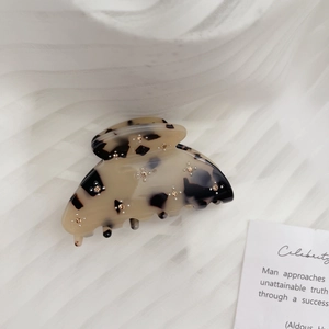 Detail of acetate hair claw clip with tortoiseshell pattern and golden flower rhinestones
