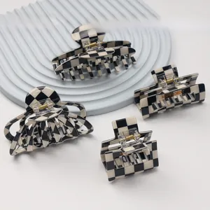 Detail shot of black and white checkerboard hair claws in acetate with brand engraving