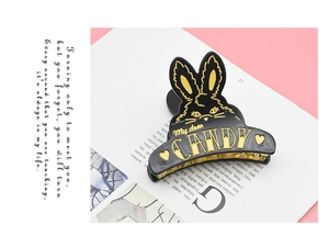 Detail of a black acetate rabbit hair claw clip with golden Candy lettering and engraving