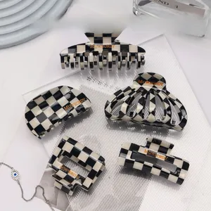 Detail of five black and white checkered hair claws with elegant gold logo accents