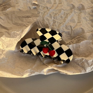 Checkerboard cherry hair claw clip displayed on vintage textured craft paper background