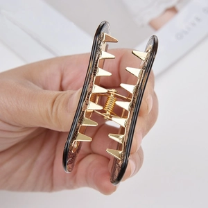 Vintage acrylic hair claw clip with dark lace pattern and gold metal teeth held in hand