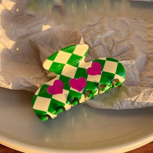Detailed view of the checkered hair claw clip with pink hearts in soft sunlight