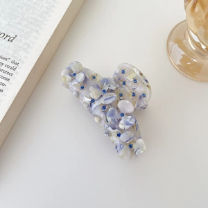 Détail de la pince à cheveux en acétate avec strass bleus et perles dorées