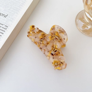 Détail d'une pince à cheveux fleur en acétate ambré avec perles argentées et strass
