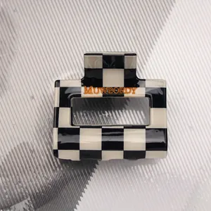 Detail view of checkerboard pattern hair claw clip with glossy finish and logo