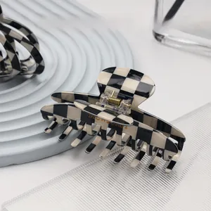 Close-up of black and white checkerboard hair claw clip with strong gold metal spring