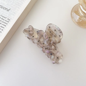 Détail d'une pince à cheveux élégante en acétate beige avec strass gris sur fond blanc