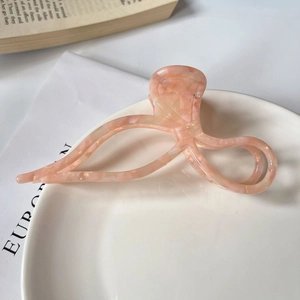 Detailed view of a pink marble acetate hair claw clip on a white ceramic plate
