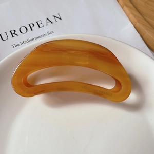 Close-up of translucent amber acetate hair claw clip featuring Creation France engraving