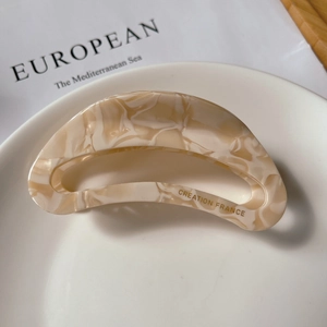 Detail view of large marble texture acetate hair claw clip with gold Creation France logo