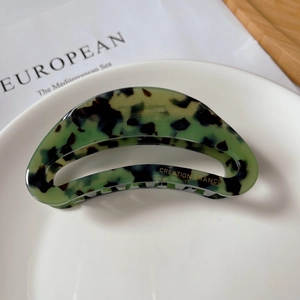 Detail of hollow arched acetate claw clip with green and black tortoiseshell texture