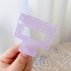 Detail of a purple rectangular acrylic hair claw clip with strong metal spring