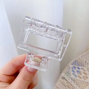 Close-up of a transparent square resin hair claw clip with golden metal spring